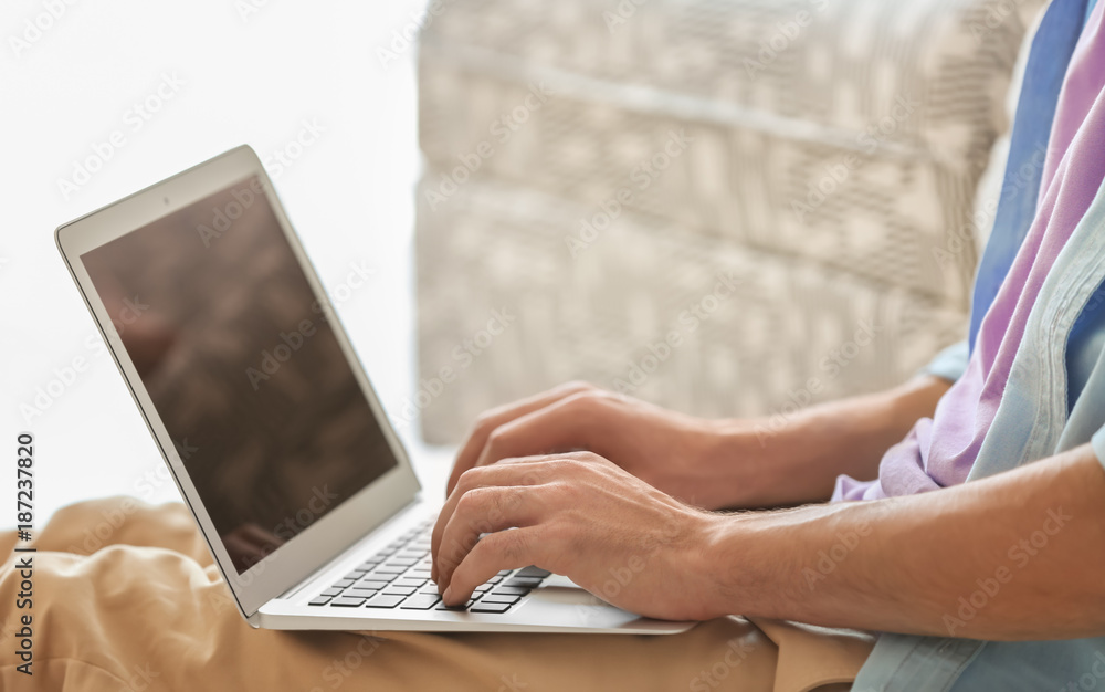 Fototapeta premium Young man using his laptop while sitting on floor indoors