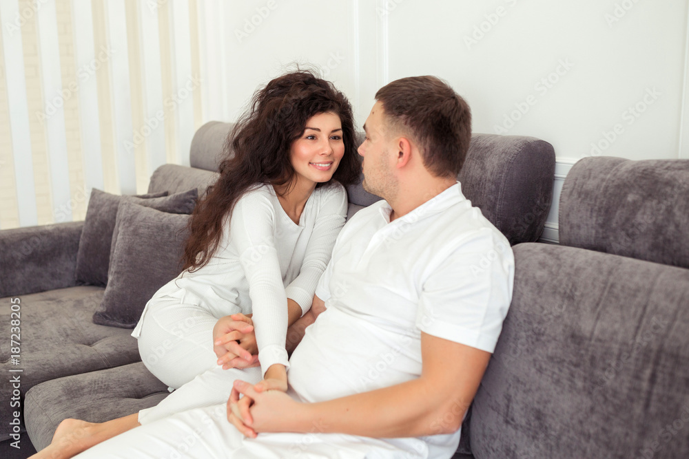 Beautiful couple smiling and hugging while spending time together at home with modern white interior Beautiful couple smiling and hugging while spending time together at home with modern white interior