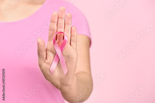 Woman showing pink ribbon on color background. Breast cancer awareness concept