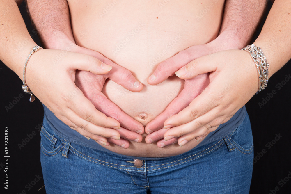Cropped image of beautiful pregnant woman and her handsome husband hugging the tummy Cropped image of beautiful pregnant woman and her handsome husband hugging the tummy