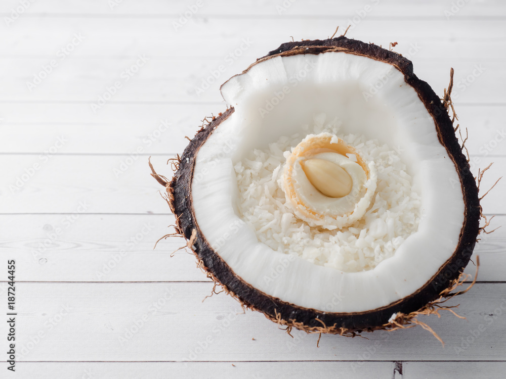 Half of the fresh organic coconut with Coconut and chocolate candy inside on wooden background Half of the fresh organic coconut with Coconut and chocolate candy inside on wooden background