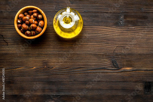 Oil as cosmetics. Haselnut oil near nut in shell on dark wooden background top view copyspace