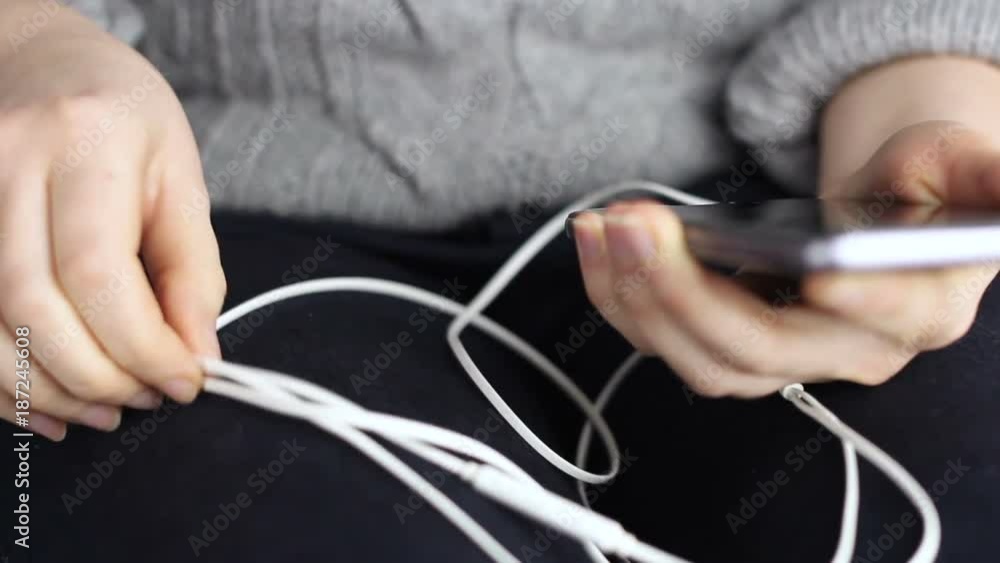 Close-up women's hands connect the headphones to the smartphone Close-up women's hands connect the headphones to the smartphone