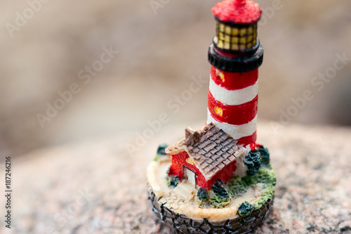 Fototapeta Naklejka Na Ścianę i Meble -  Closeup macro little red and white toy lighthouse. Vintage background.