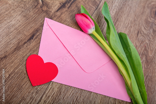 Envelope and tulip on a wooden table