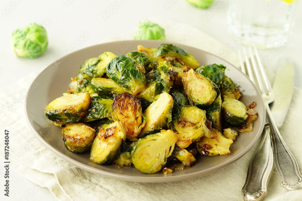Homemade Roasted Brussel Sprouts with salt, pepper and onions in a beige plate on grey background. top view. copy space Homemade Roasted Brussel Sprouts with salt, pepper and onions in a beige plate on grey background. top view. copy space
