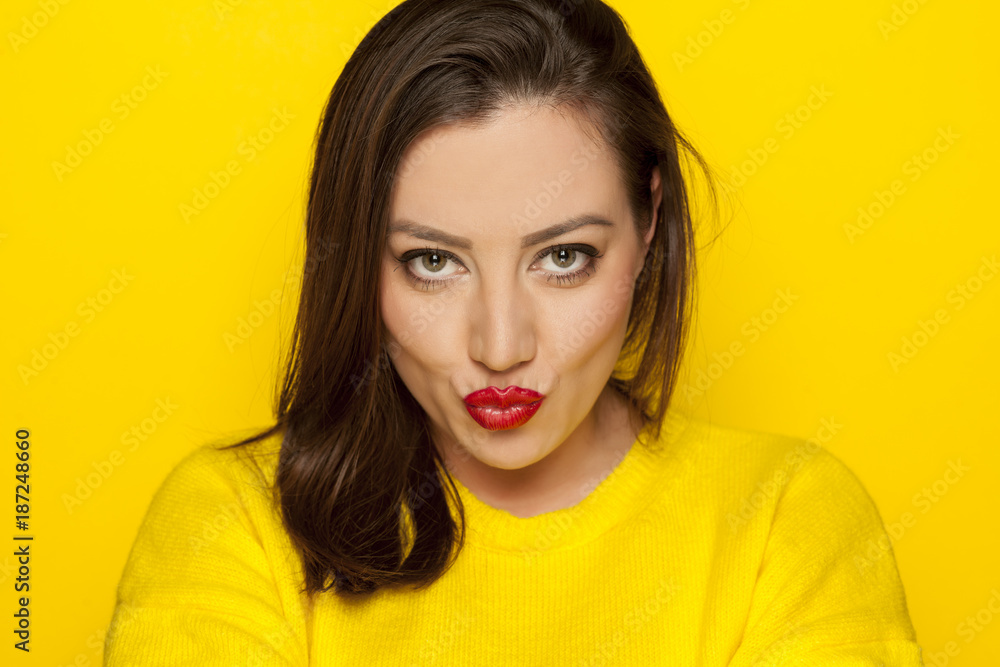 beautiful sexy woman in a yellow blouse with kissing gesture on a yellow background beautiful sexy woman in a yellow blouse with kissing gesture on a yellow background