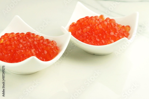 red caviar in white plates on a marble table. copy space