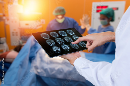 Smart health care internet of things and hospital management technology concept. Doctor using x-ray brain tablet for check status of patient in operating room and surgery doctor in smart hospital. photo