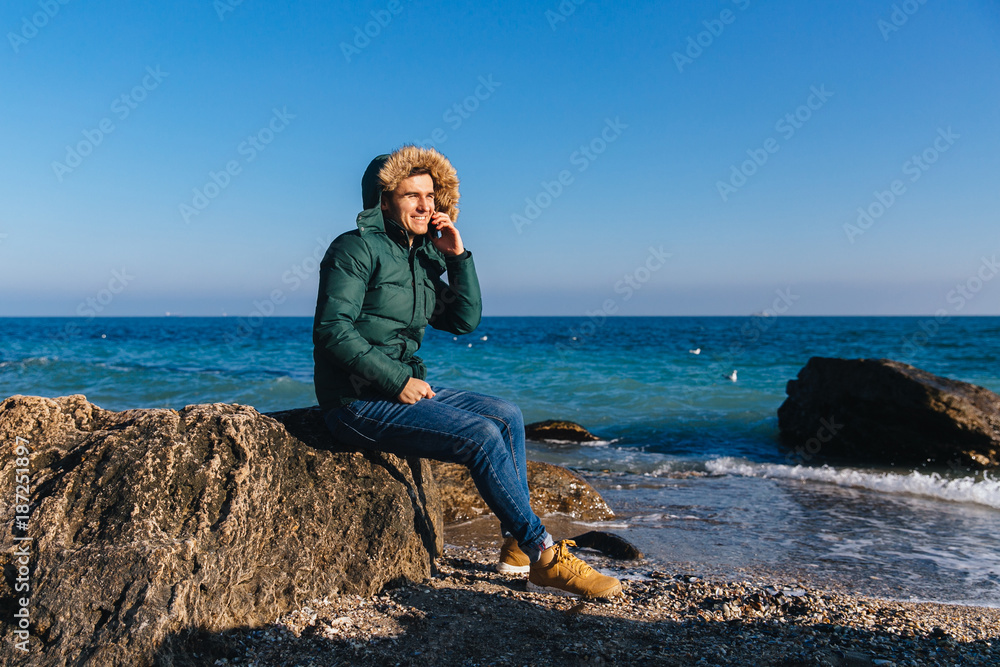 Smiling man talking on the phone by the sea