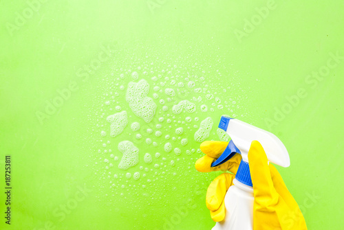 Person, a hand in a rubber glove in the picture, removes and washes, the green background copy space
