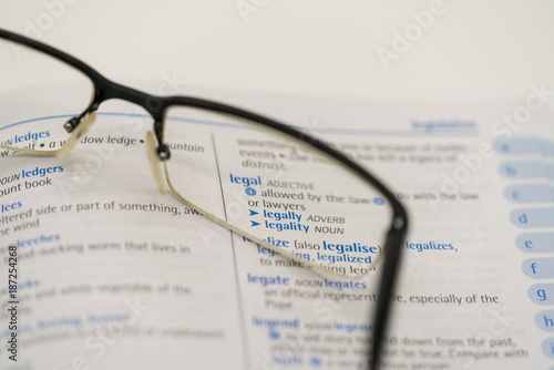 Dictionary showing the word legal through a pair of reading glasses