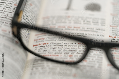 Dictionary showing the word business  through a pair of reading glasses