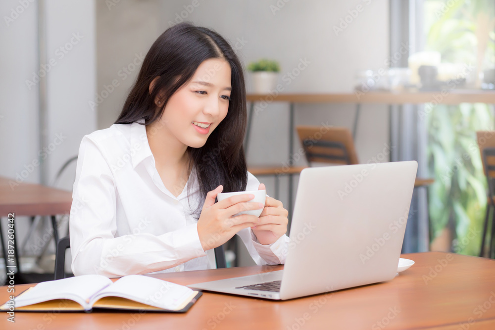 Beautiful asian young woman working online on laptop sitting at coffee shop, professional female freelancer using notebook computer with connect to internet for distance job. Beautiful asian young woman working online on laptop sitting at coffee shop, professional female freelancer using notebook computer with connect to internet for distance job.