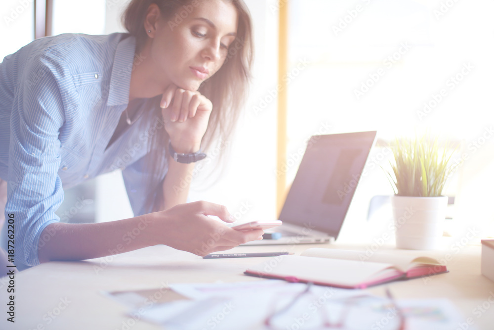 Beautiful young business woman sitting at office desk and talking on cell phone. Business woman Beautiful young business woman sitting at office desk and talking on cell phone. Business woman