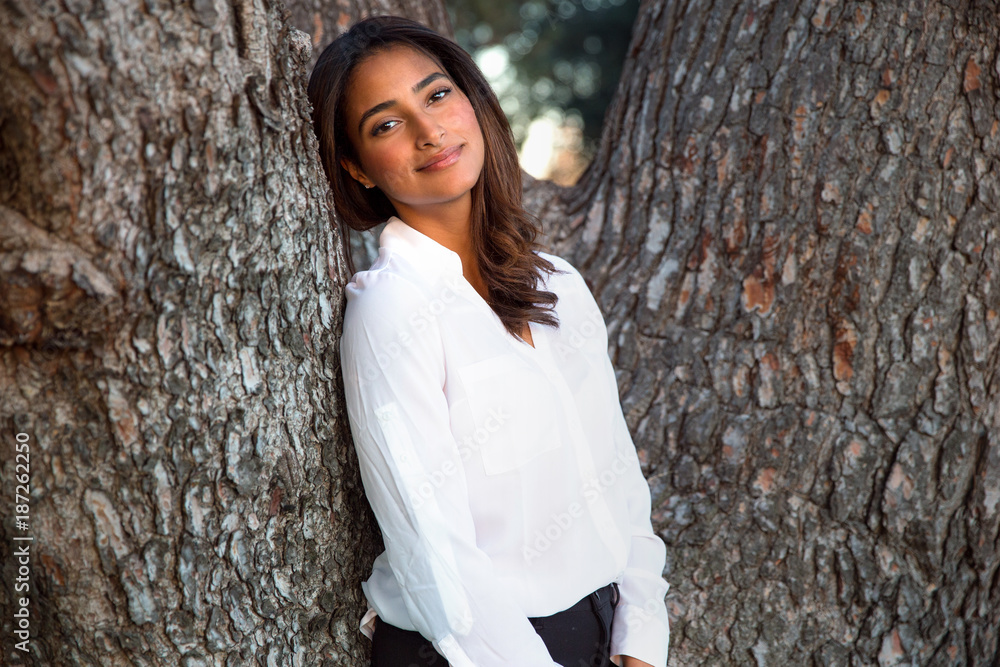 Naklejka premium Sweet sincere beautiful woman of mixed ethnicity standing caring for a tree in nature