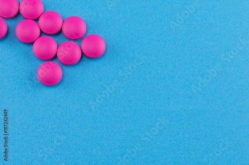 pink round pills on blue background with copy space