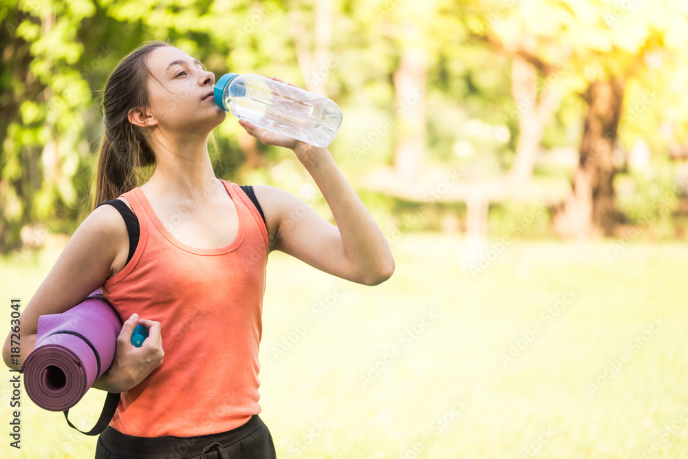 Beautiful girl drinking water after practicing yoga in the park. Beautiful girl drinking water after practicing yoga in the park.