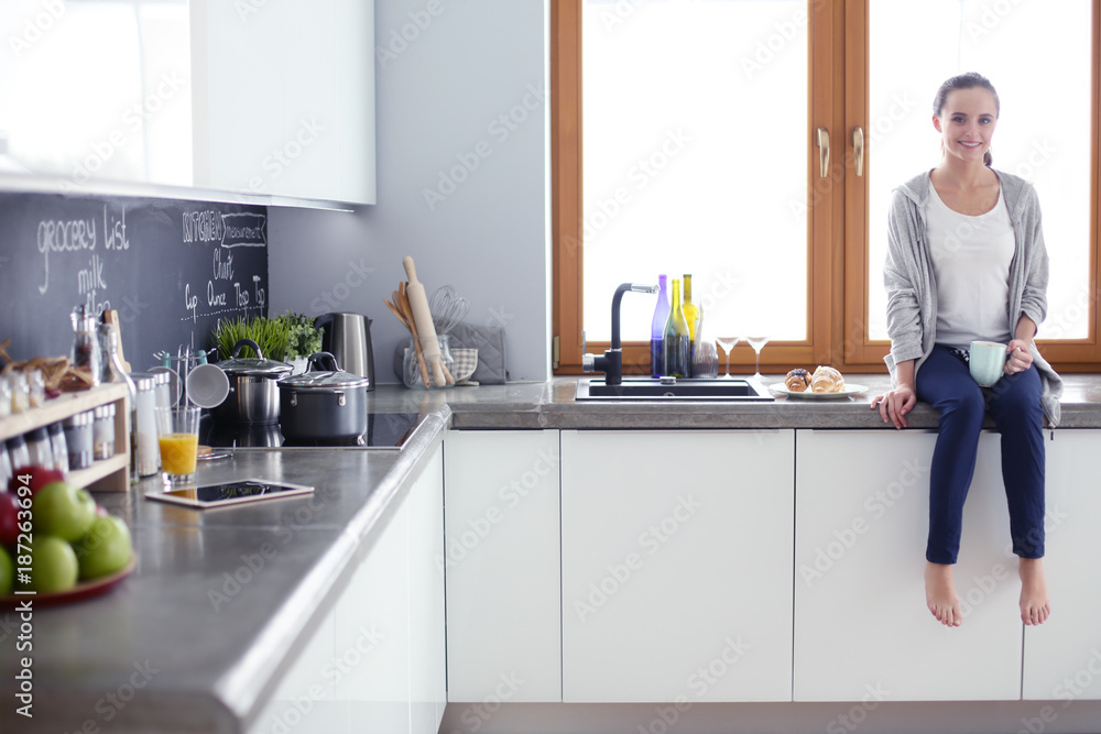 Beautiful young woman using a digital tablet in the kitchen. Beautiful young woman using a digital tablet in the kitchen.