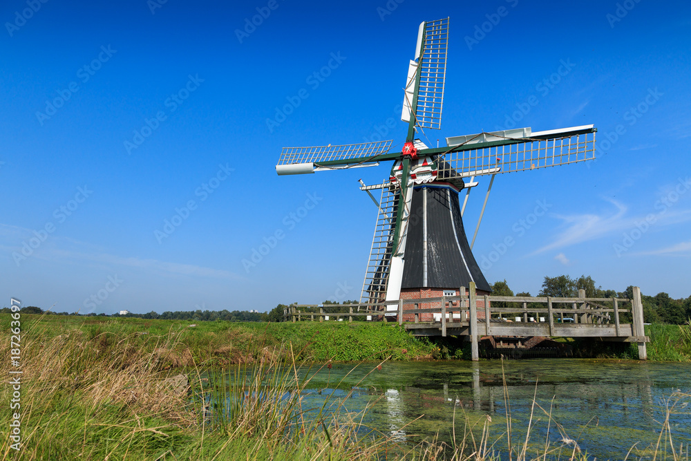 Historic windmill in water landscape. Windmill De Helper near Haren in Groningen, The Netherlands.