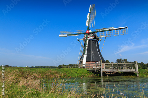 Historic windmill in water landscape. Windmill De Helper near Haren in Groningen, The Netherlands.