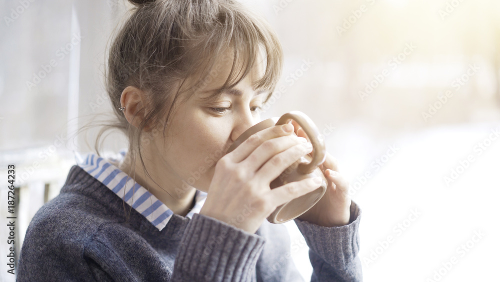 Beautiful woman wearing a gray sweater is enjoying her tea in a cafe and daydreaming. Portrait shot Beautiful woman wearing a gray sweater is enjoying her tea in a cafe and daydreaming. Portrait shot