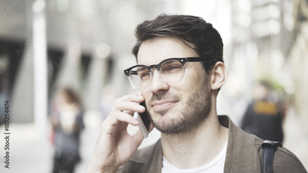 Fototapeta premium Front view portrait of a businessman using a smart phone in the street.