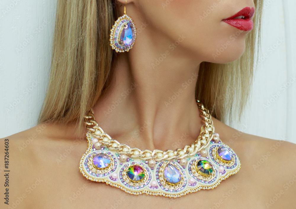 Beautiful female model with blond hair and red lips in handmade accessories fashion jewelry necklace, earrings with pearls and crystals in blue and gold color set, fashion style, art, creative design