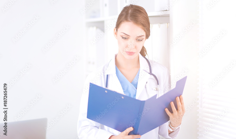 Smiling female doctor with a folder in uniform standing at hospital Smiling female doctor with a folder in uniform standing at hospital