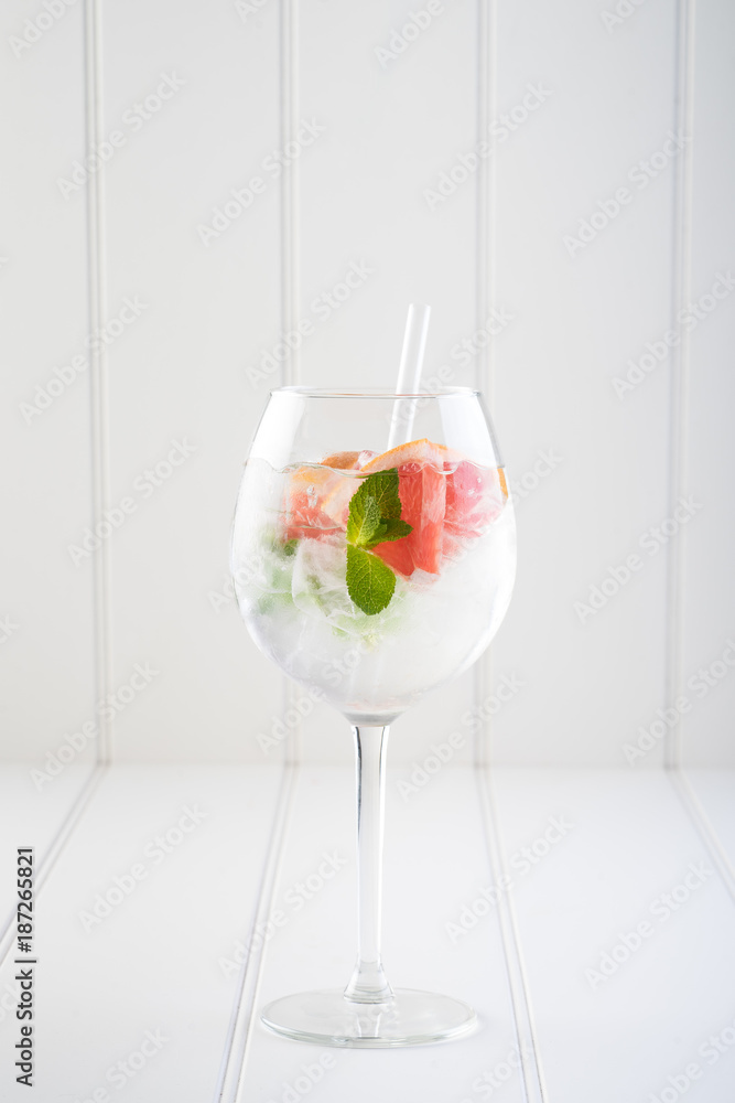 gin and tonic alcohol drink cocktail glass ice fruit garnish plain black white background