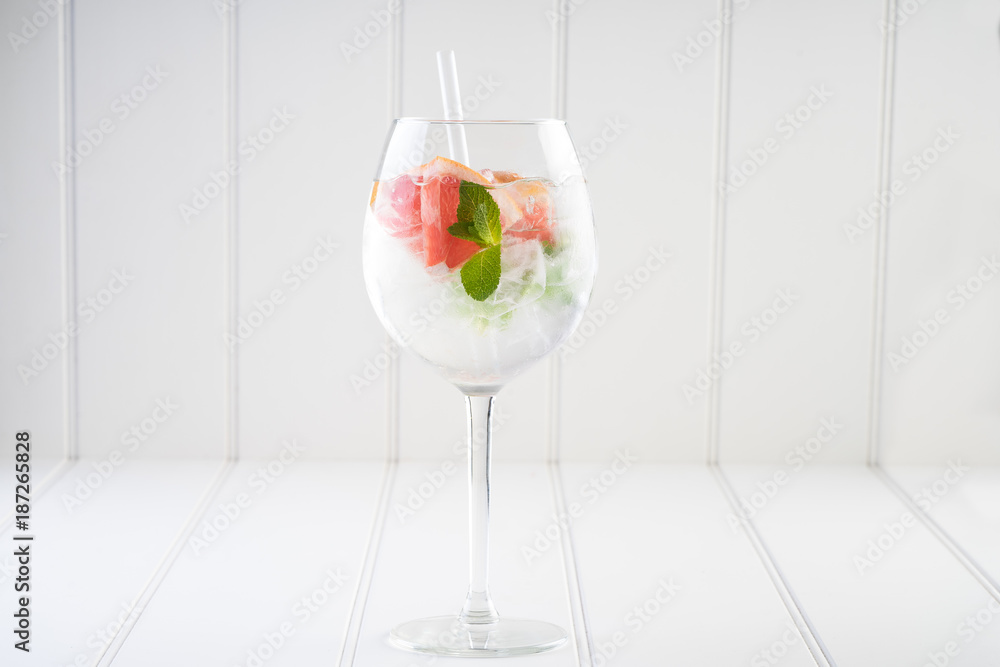 gin and tonic alcohol drink cocktail glass ice fruit garnish plain black white background