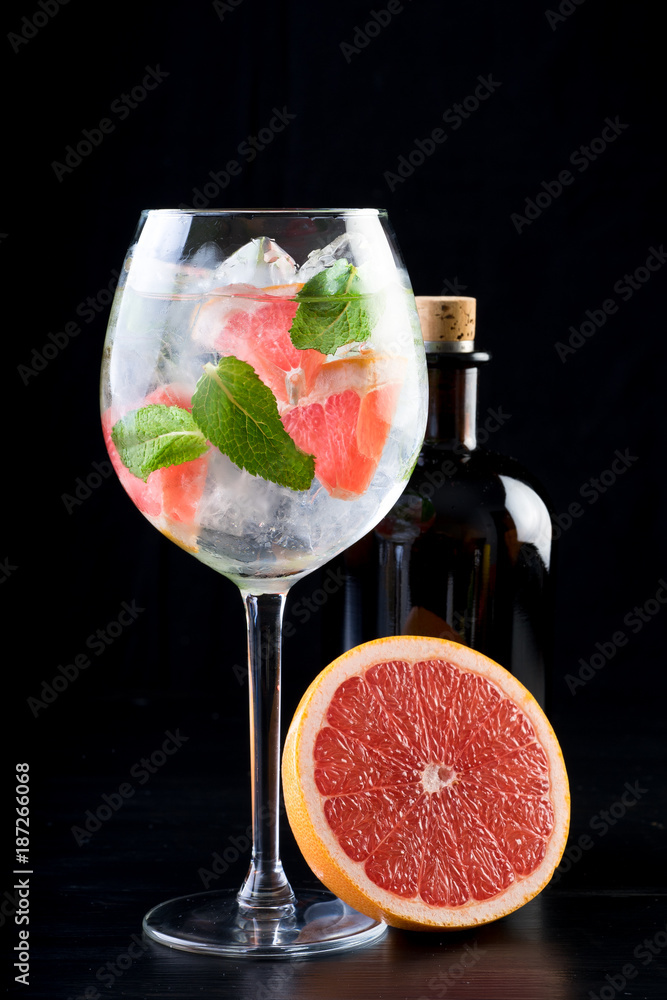 gin and tonic alcohol drink cocktail glass ice fruit garnish plain black white background