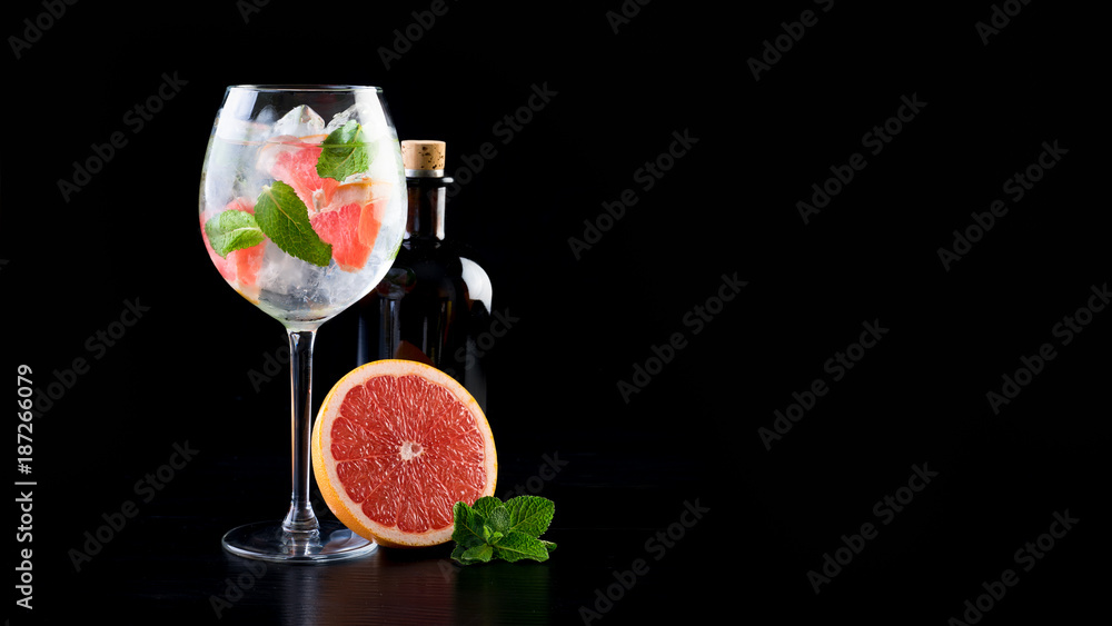 gin and tonic alcohol drink cocktail glass ice fruit garnish plain black white background