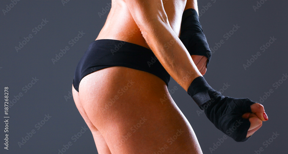 Fototapeta premium Muscular young woman standing on gray background