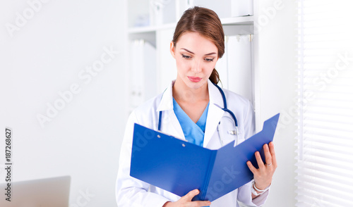 Smiling female doctor with a folder in uniform standing at hospital