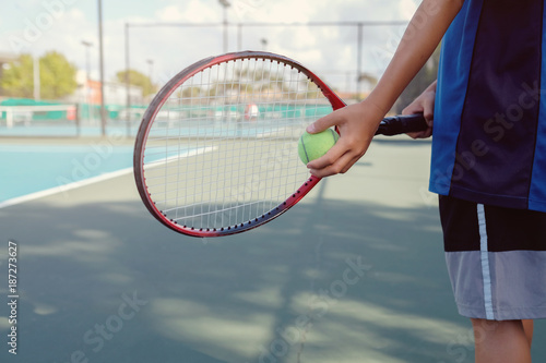 Young boy tennis player on outdoor blue court © SewcreamStudio