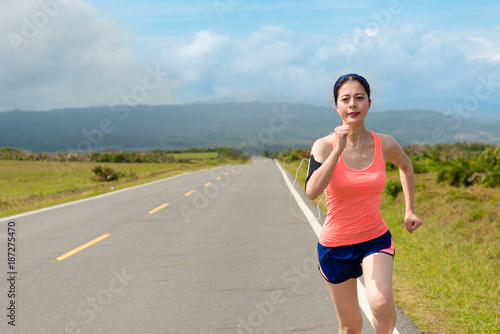 smiling female runner going to countryside road