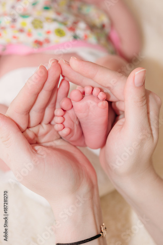 Mom keeps the baby's legs in the palms of his hands