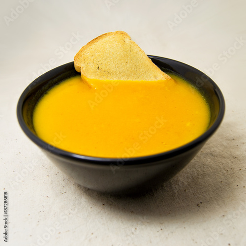 delicious pumpkin pured soup with potatoes and zwiebacks bread slices. for vegetarian, vegan and healthy concept photo
