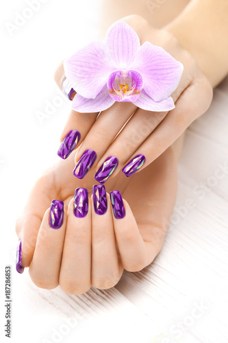 beautiful purple manicure with orchid, candle and towel on the white wooden table.