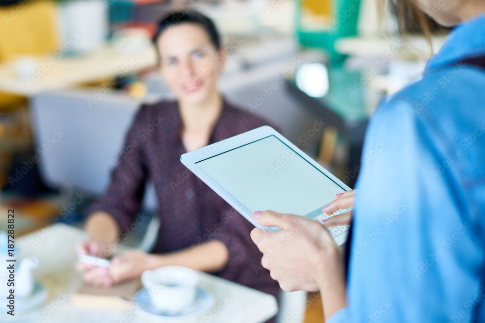 Unrecognizable waitress using digital tablet while taking order from pretty client at restaurant, focus on foreground Unrecognizable waitress using digital tablet while taking order from pretty client at restaurant, focus on foreground