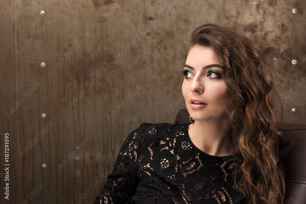 Horizontal portrait of a beautiful woman looking to the side. Black lace dress, long wavy hair, professional makeup
