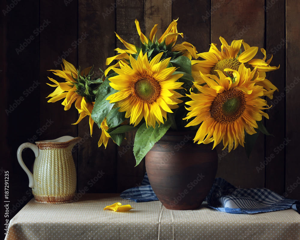 Fototapeta premium Bouquet of sunflowers in a clay jug on the table.
