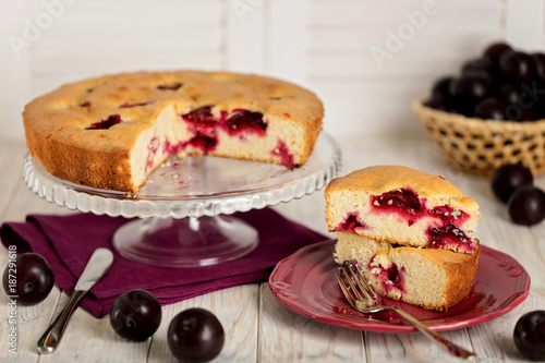 Homemade plum cake on a glass stand.