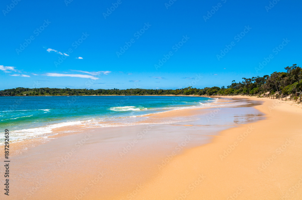 Picturesque sand beach with soft waves and blue sky