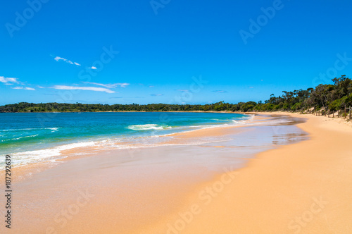 Picturesque sand beach with soft waves and blue sky