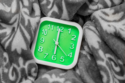 Green alarm clock on the bed. It alarm at 6.00 AM on workday.Time for sunrise.Process with monotone.