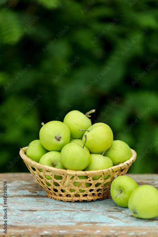 Homemade rustic green apples in a basket on an old stool. Homemade rustic green apples in a basket on an old stool.