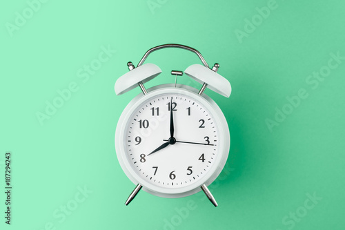 vintage alarm clock on the middle of solid light green color background
