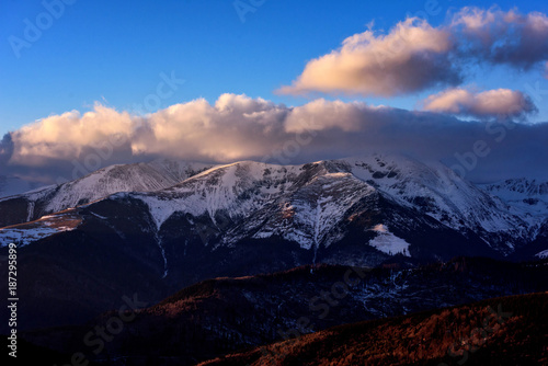 Mountain winter scenery in the high Carpathian mountains of Romania with snow, clouds in the sunset